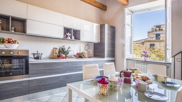 Una cocina moderna con un ventanal grande, una mesa de comedor lista para el desayuno y vistas de la ciudad.