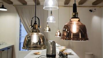 A kitchen with wooden beams, pendant lights, a wooden cutting board, a toaster, and a coffee maker.