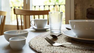 A dining table with white bowls, a glass, and cutlery.