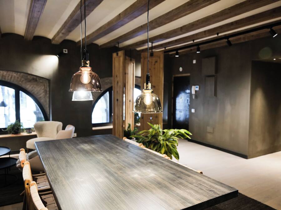 Ein modernes Interieur mit einem langen Holztisch, hängenden Pendelleuchten und einem großen Fenster mit Blick.