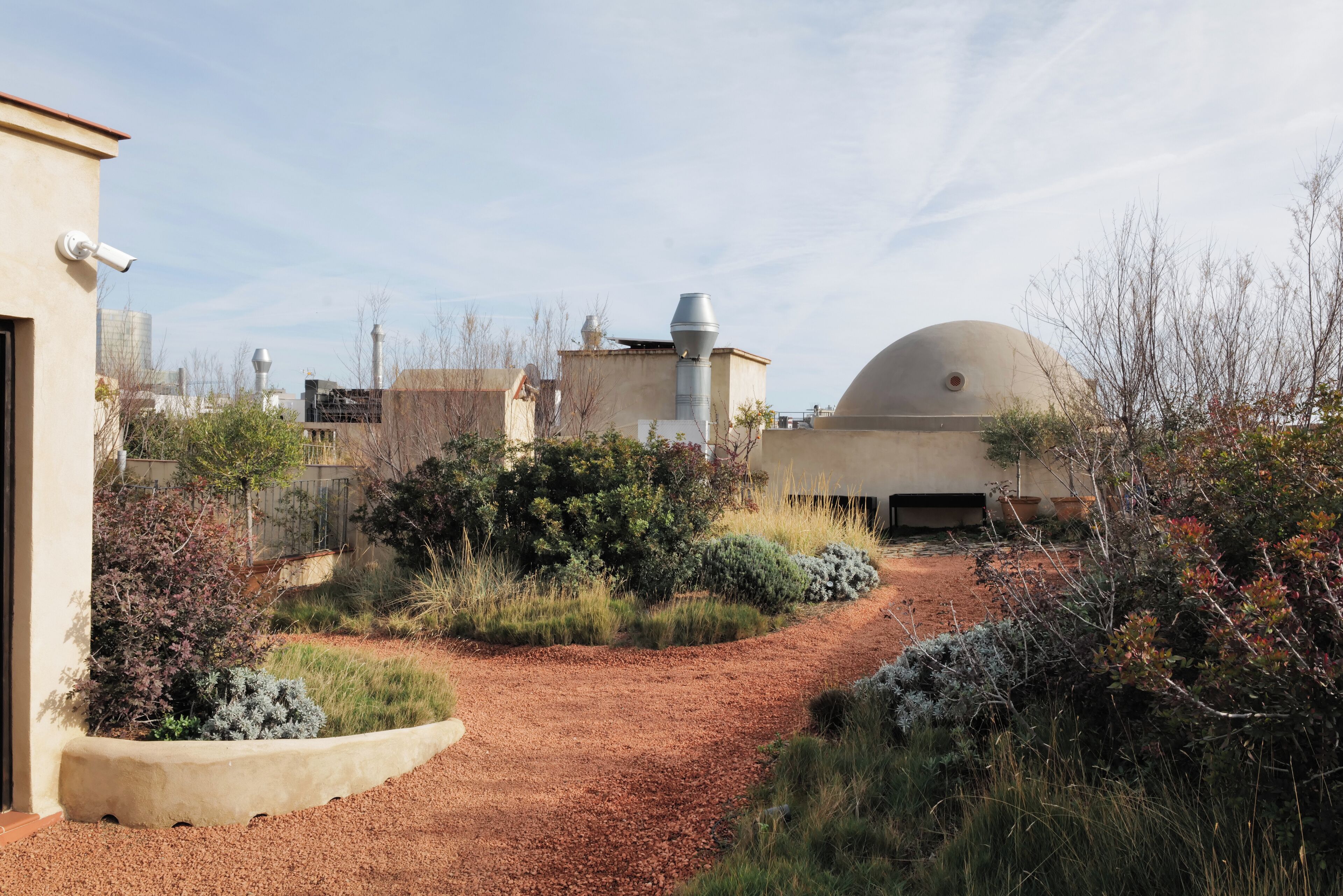 A garden pathway leading to a building with a dome-shaped structure.