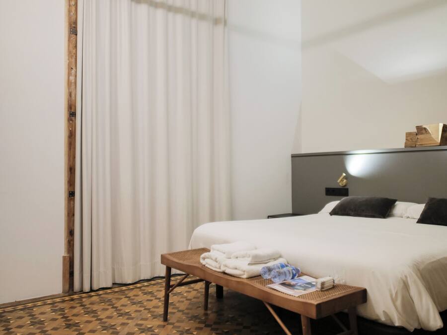 Une chambre d’hôtel avec un lit, une table de chevet avec des serviettes, une tête de lit avec une lampe et un sol à motifs.
