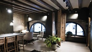 A modern interior with exposed beams, a brick wall, and a large arched window. - Porxos Garden (Barcelona)