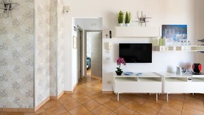 A modern living room with a flat-screen TV, white cabinetry, and a tiled floor. - Corrado Residence (Blu) - Apartment near Marzamemi (Reitani)