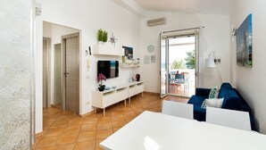 A modern living room with a white TV, white console, and a blue sofa. - Corrado Residence (Blu) - Apartment near Marzamemi (Reitani)