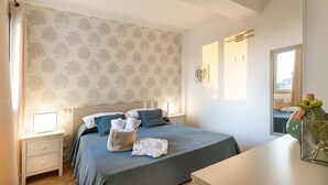 A neatly arranged bedroom with a bed, bedside tables, a dresser, and a window with a view. - Corrado Residence (Alba) -Apartment near Marzamemi (Reitani)