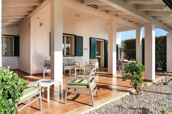 A covered outdoor patio with a seating area, a small table, and a potted plant. - Corrado Residence (Acqua) near Marzamemi (Reitani)