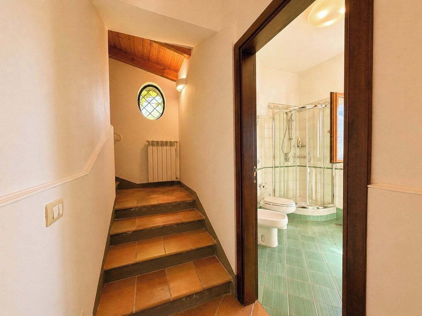 A staircase leading to a bathroom with a glass shower enclosure and a toilet.