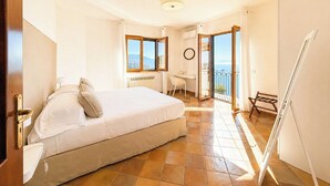 Une chambre avec un lit, un bureau, une chaise et un balcon offrant une vue.