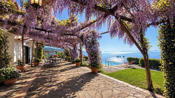 Une terrasse couverte avec un sol en pierre, des sièges d’extérieur et une vue sur la mer.