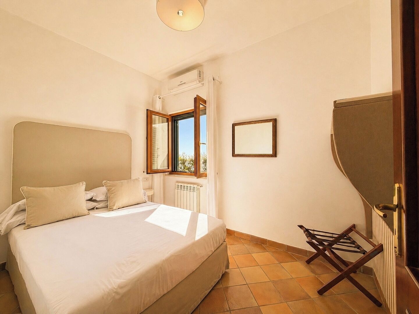 Een slaapkamer met een bed, een raam, een radiator en een spiegel.