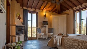 Ein gemütliches Schlafzimmer mit Bett, Fernseher, Schreibtisch und Stuhl.