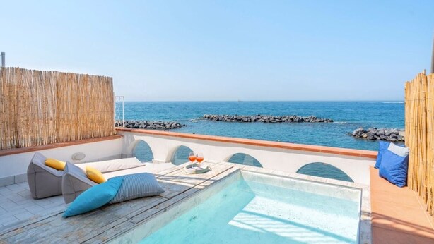 A rooftop pool area with a view of the sea, featuring a small pool, lounge chairs, and a bamboo fence. - Villa Mia - Sea front private villa close to town (Napoli)
