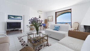 A modern living room with a television, sofa, and a view of the sea. - Villa Mia - Sea front private villa close to town (Napoli)