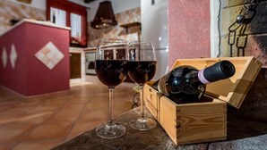 A wooden wine box with a bottle and two wine glasses on a stone countertop.