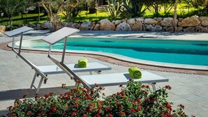 A poolside area with lounge chairs and a stone wall.