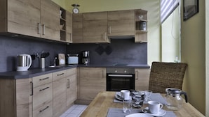 A compact kitchen with wooden cabinets, a built-in oven, and a dining area with a table set for two.