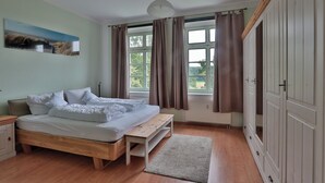 Ein Schlafzimmer mit einem hölzernen Bett, einer Sitzbank, einem Nachttisch, einer Heizung und einem Kleiderschrank.