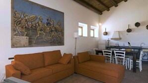 A living room with a large historical painting, a sofa, and a dining area with chairs and a table. - Ragusa Apartments (Blu) - apartment near Ragusa (Ragusa)