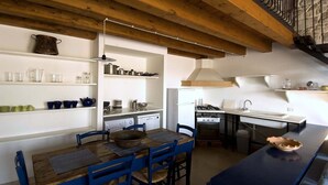 A compact kitchen with a dining area, wooden beams, and a built-in stove. - Ragusa Apartments (Grigio) - apartment near Ragusa (Ragusa)