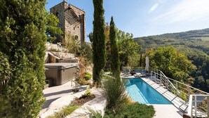 Un espace piscine doté d’un jacuzzi, de chaises longues et, en arrière-plan, d’une tour en pierre.