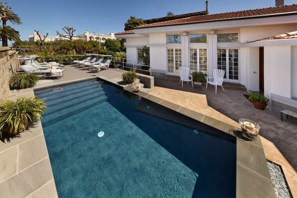 Ein Schwimmbecken mit Liegestühlen und einer Terrassenfläche.