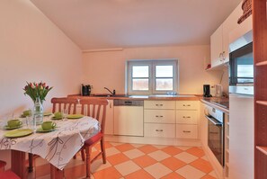 A compact kitchen with a window, a dining table with chairs, and a refrigerator. - Fernab vom Tourismustrubel Können Sie in Dieser Romantisch Gelegenen Ferienwohnung mit Ruhe Ihre Auszeit vom Alltag Genießen (Pepelow)