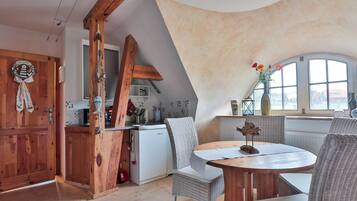 Ein Loft-Zimmer mit Essbereich, Küche und einem großen Fenster.