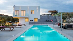 Une maison moderne dotée d’une piscine, d’un espace salon extérieur et d’un escalier menant à une terrasse.
