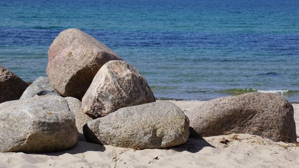Une plage avec de gros rochers et une vue dégagée sur l’océan.