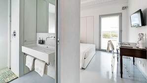 Une chambre moderne avec un grand lit, une table de chevet, un téléviseur et une vue sur l’extérieur.