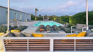 Un espace aménagé au bord de la piscine, comprenant une piscine, des sièges et un patio couvert.