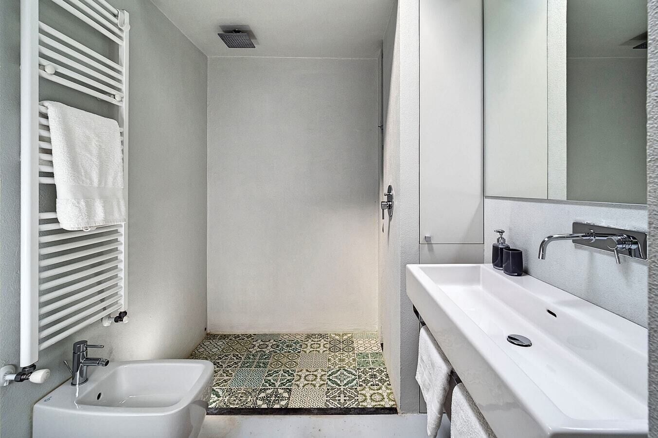 A modern bathroom with a shower, a bidet, and a sink with a mirror.