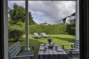 Relax in a serene garden setting with a table for four, bench, and lounge chairs.