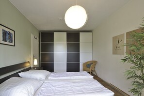 Relax in a stylish room with a large bed, bedside table, and wicker chair.