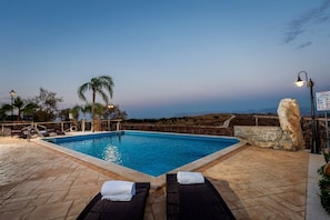 Ein Swimmingpool mit Liegestühlen und einem gepflasterten Weg.