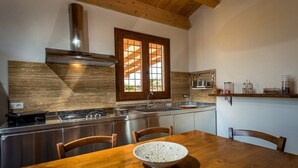 Een moderne keuken met een houten tafel, een fornuis en een raam met zonwering.