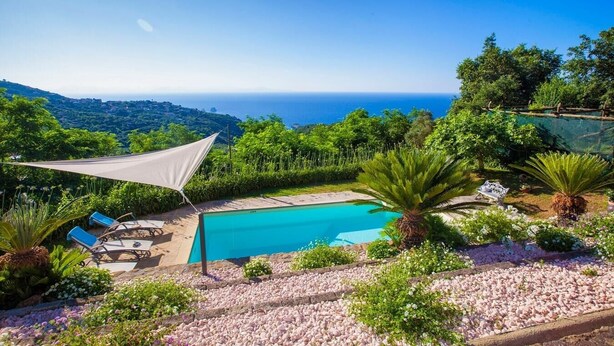 A pool area with a view of the ocean, surrounded by lush greenery and a shaded seating area. - Villa Carina with sea views (Sant'Agata Sui Due Golfi)