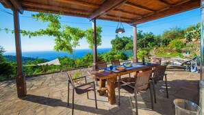 An outdoor patio with a wooden table and chairs, overlooking a scenic view of the sea and lush greenery. - Villa Carina with sea views (Sant'Agata Sui Due Golfi)