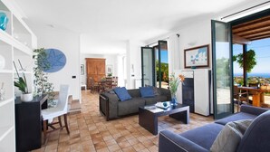 A modern living room with a sofa, coffee table, and a dining area with chairs and a table. - Villa Carina with sea views (Sant'Agata Sui Due Golfi)