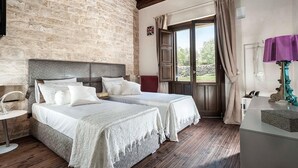 Un dormitorio con dos camas, una pared de piedra, techo de madera y vistas a través de un ventanal.