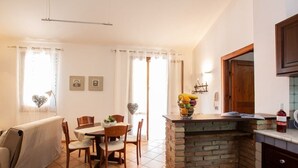 A cozy living room with a dining area, a fireplace, and a kitchen counter. - Villa Colletta + Annex - villa near Scopello (Castellammare del Golfo)