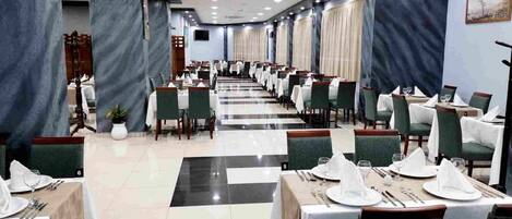 A banquet hall with tables set for dining, featuring a checkered floor pattern and a long, straight layout.