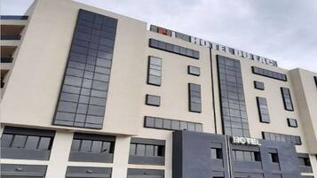 Un hôtel moderne, avec une façade sobre, de grandes fenêtres et une enseigne « HÔTEL » bien visible.