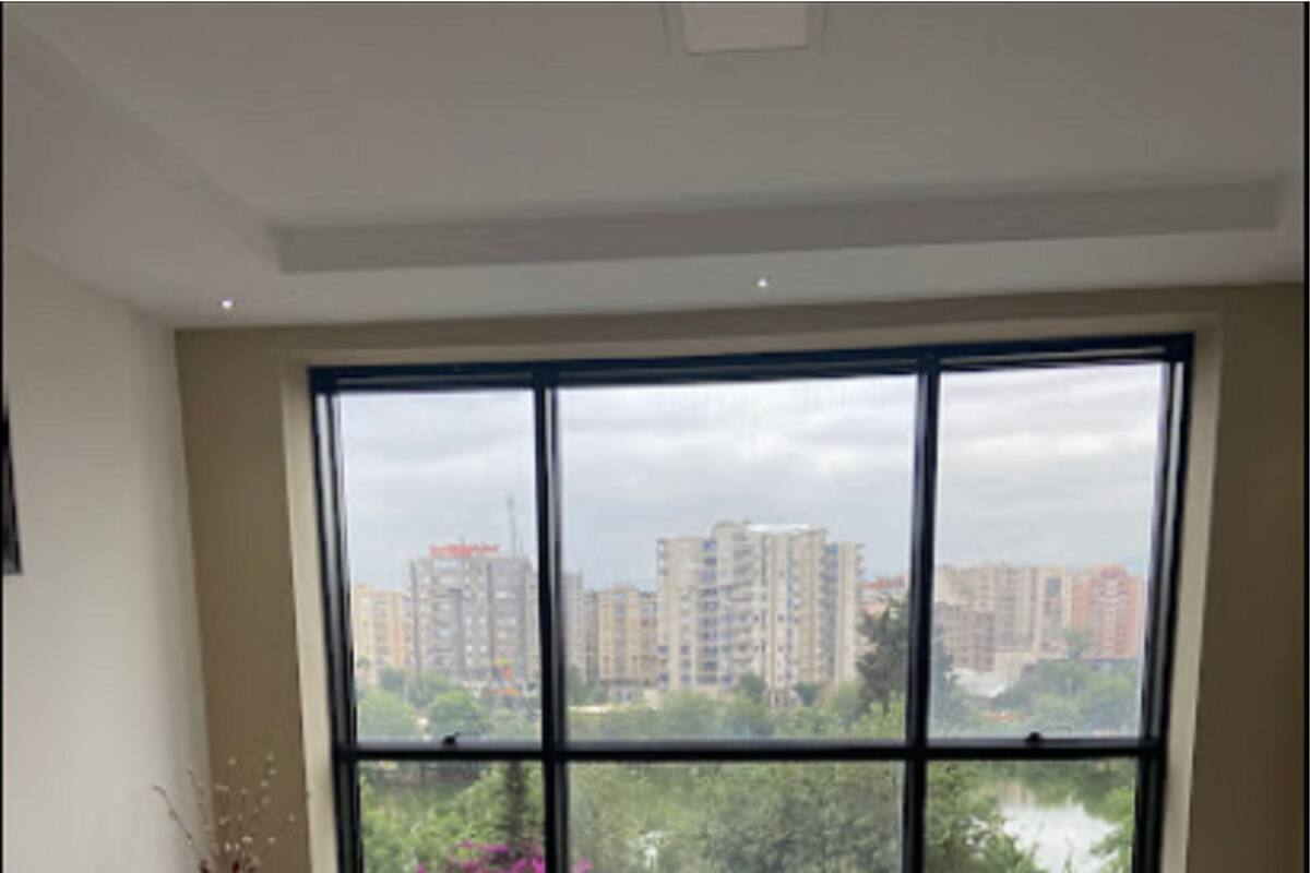Ein modernes Wohnzimmer mit einem großen Fenster, zwei Sofas, einem kleinen runden Tisch und einem gemusterten Teppich.