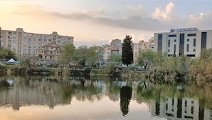 A hotel with a modern facade, situated beside a calm body of water with reflections. - Hôtel du Lac Béjaïa (Béjaïa)