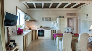 A compact kitchen with a dining area, wooden beams on the ceiling, and a television on the counter. - Villa Del Fiore - Private villa with pool (Marausa)