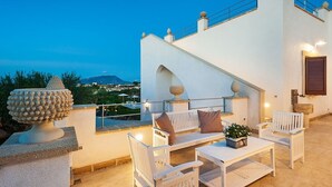A terrace with white furniture, a stone sculpture, and a view of a mountain. - Villa Del Fiore - Private villa with pool (Marausa)