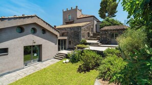 Una villa moderna con fachada de piedra, un pequeño jardín y una escalera que lleva a una terraza de madera.