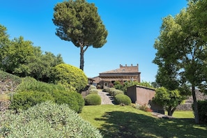 A house with a tiled roof, surrounded by well-maintained gardens and a large tree.